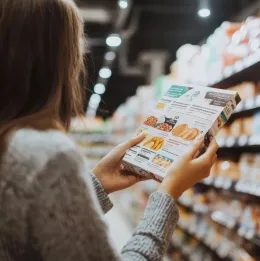 Woman in grocery store reads nutrition label on packaged food
