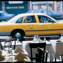 A New York City taxi can be seen driving by through a restaurant dining room window
