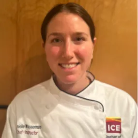 ICE Instructor Danielle Wasserman in chef whites against a wood-grained background.