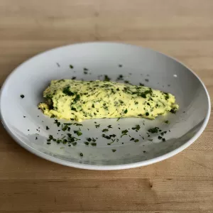 A French omelet garnished with fresh herbs.