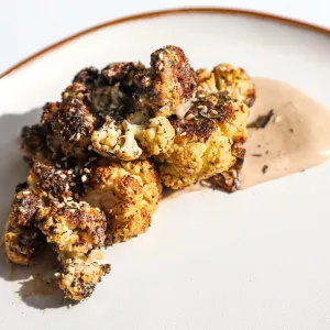 Browned cauliflower and miso-sesame sauce on a white plate