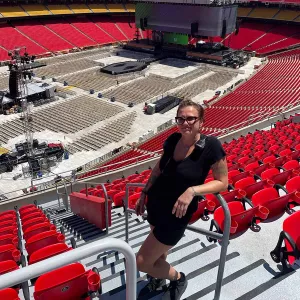 Chef Sandra Gajovsky smiles in front of rows of red chairs lining a stadium