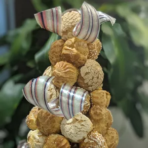 A celebratory croquembouche is accented with ribbon.