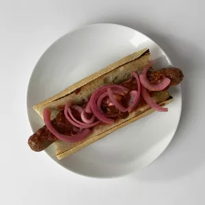 Chef Frank's lamb hot dog with pickled red onions and harissa