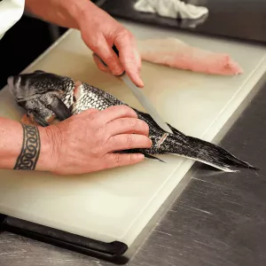 photo of chefs's hands using filet knife to cut into a whole fish