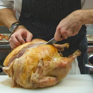 A cooked turkey is carved on a white cutting board