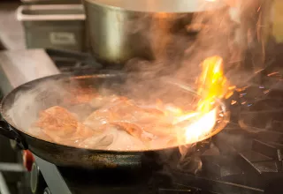 A pan flares up while sauteing chicken