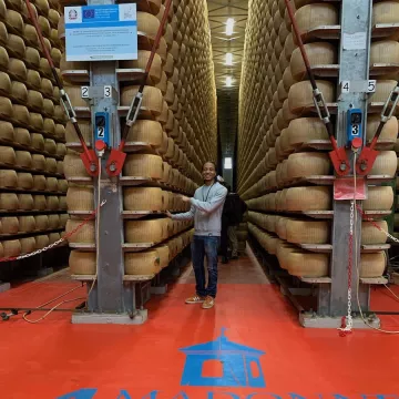 Aaron Beasley poses among cheese wheels in Modena, Italy