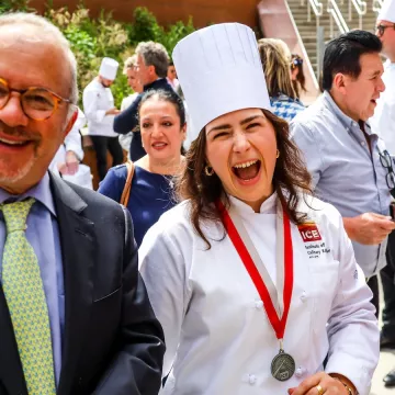 ICE graduate Alessandra Ciuffo, a brunette woman, smiles in an ICE white chef's coat and hat