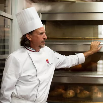 Chef Sim Cass stands in front of an oven