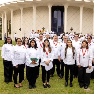 ICE online culinary school graduates smile with Chef-Instructor Shawn Matijevich at ICE's commencement ceremony