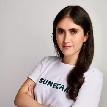 Danielle Krueger, a woman with long brown hair wears a grey shirt that reads "Sunbear"