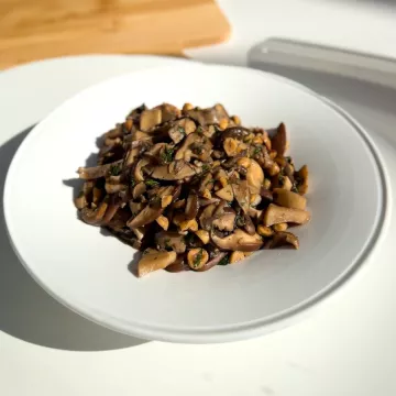 Sauteed mushrooms and hazelnuts on a white plate