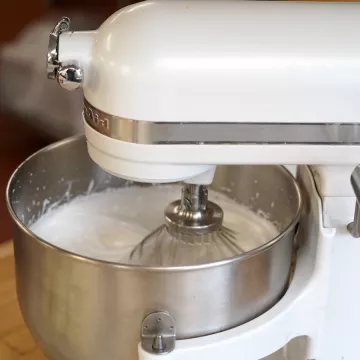 A white KitchenAid stand mixer whipping white buttercream