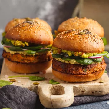 Vegan burgers sit on a wooden cutting board