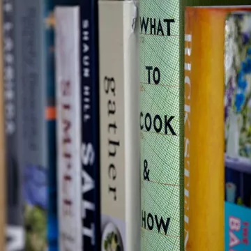 A stack of cookbooks on a shelf