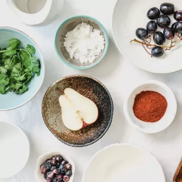 view of table with plates of pears grapes basil coconut and seeds