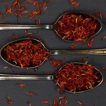 Red saffron leaves sit on three metal spoons