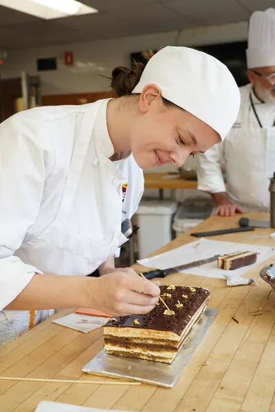 An ICE Professional Cake Decorating student perfecting a chocolate cake.