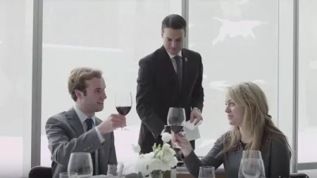 Guests share wine at a table, served by John Ragan, who teaches the master wine course at ICE