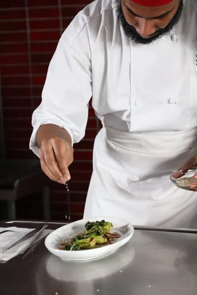 a Culinary Nutrition student add the finishing garnish to a dish