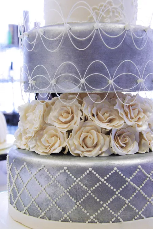 A blue-silver cake with white flowers from the ICE Professional Cake Decorating Program