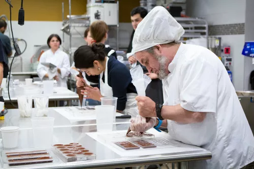 A continuing education student pipes tempered chocolate into molds in the ICE Chocolate Lab