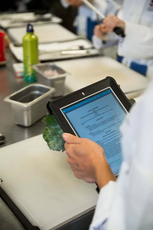 An ICE instructor with an iPad in culinary school class