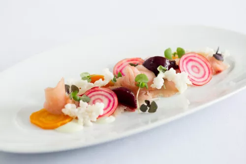 A plated dish of seafood crudo and raw vegetables