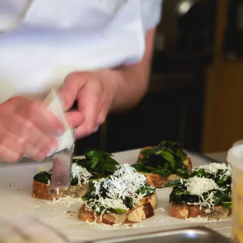 chef shaving cheese on crostini dish at culinary event in NYC