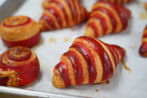 Golden brown croissants and puff pastries fresh from the oven on parchment paper-lined baking sheet