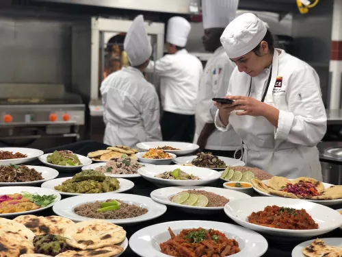 A Culinary Arts student photographs her class's spread of Latin food