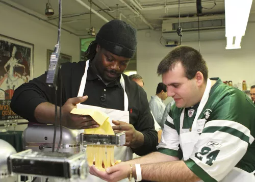 A New York Jets football player makes fresh pasta with a fan at ICE 