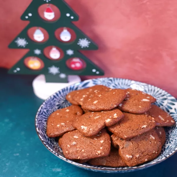 Brown square ginger snap cookies in a blue and white patterned bowl on a brown background