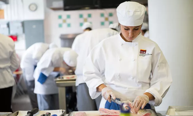 A culinary arts student breaks down a fish in class at the Institute of Culinary Education