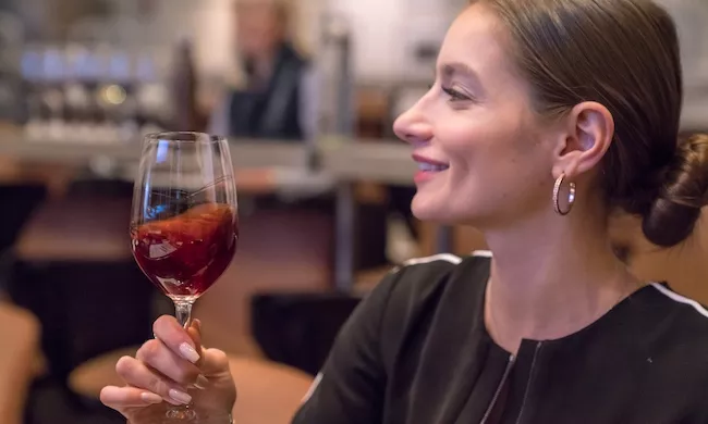 A wine student holds a glass of red wine