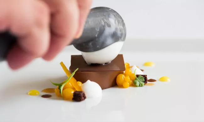 An ICE pastry student plates a chocolate dessert with sorbet