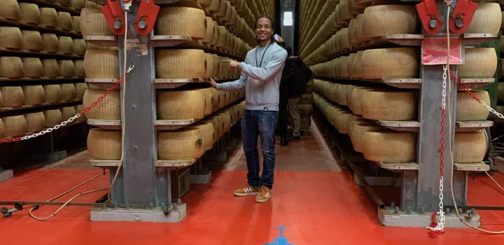 Aaron Beasley poses among cheese wheels in Modena, Italy