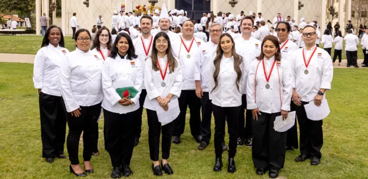 ICE online culinary school graduates smile with Chef-Instructor Shawn Matijevich at ICE's commencement ceremony