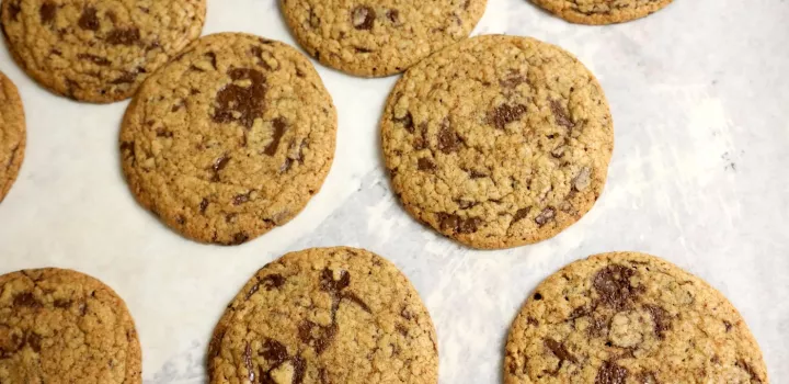 Rows of chocolate chip cookies sit on a tray