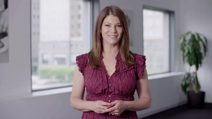 ICE alum Gail Simmons, a woman with brown hair wearing a red dress, smiles for the camera in a sunny room.