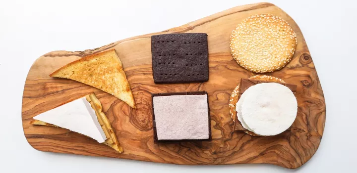 Three untoasted, open faced, s'mores on a wooden board