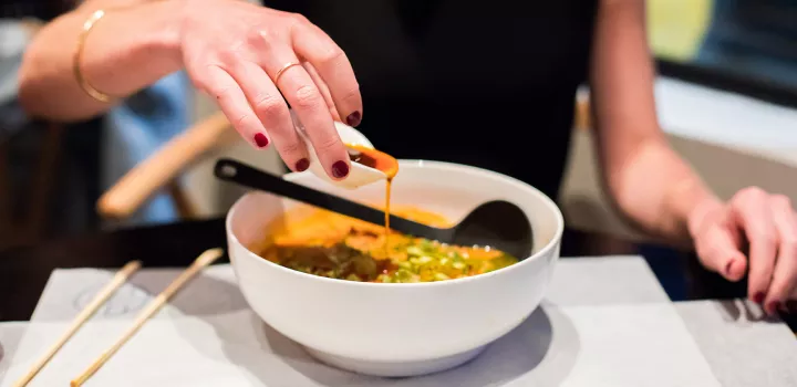 A diner pours sauce into a bowl at Little Tong Noodle Shop.
