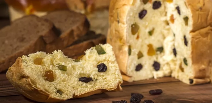 A panettone, a round cake of bread with fruit inside, sits with a slice removed