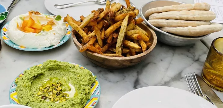 Labneh, Pistachio dip, French fries, pita on a table