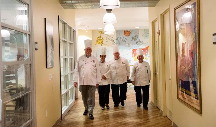 ICE instructors walk down a culinary school lobby together
