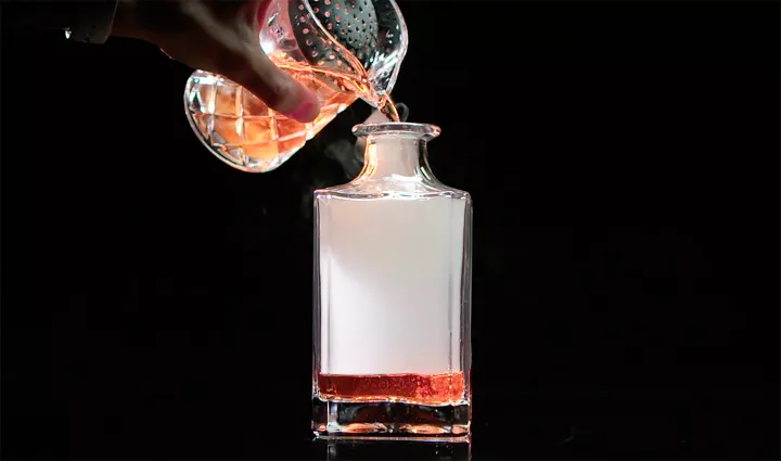 Liquid smoke fills a flask for a cocktail made with the Polyscience smoking gun